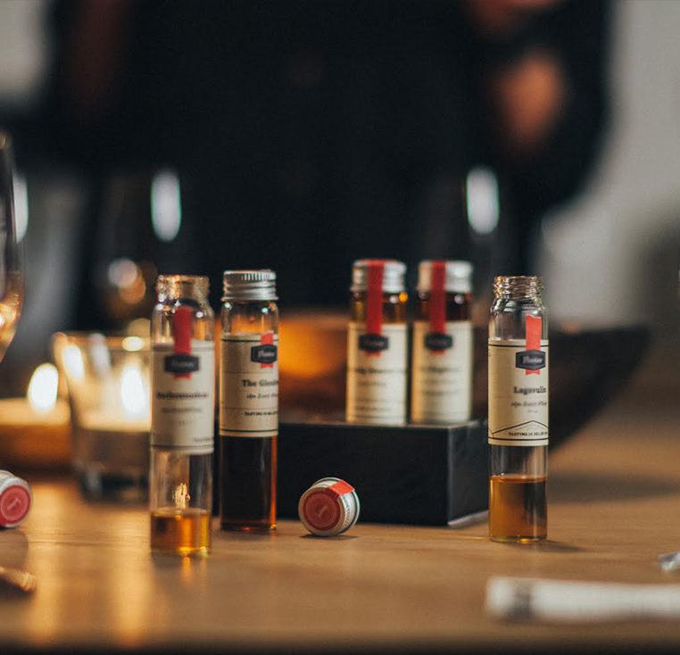 photo de mignonnette de dégustation de rhum au centre de l'image posé sur une table en bois