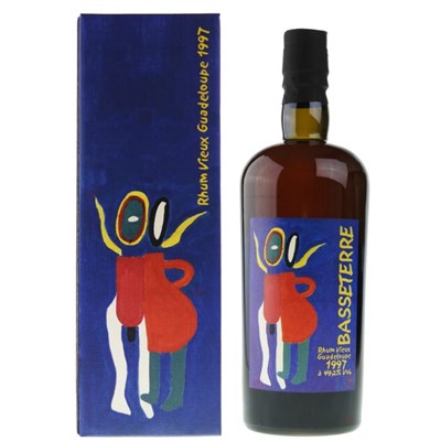 Une bouteille de rhum Vieux Basseterre 1997 de 70 cl, debout sur une table en bois. La bouteille est en verre transparent, avec une étiquette blanche et bleue. L'étiquette porte le nom du produit, le millésime, la teneur en alcool et le logo de la distillerie Montebello.