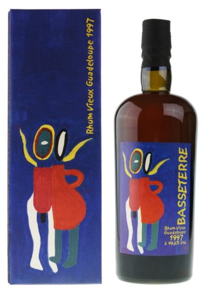 Une bouteille de rhum Vieux Basseterre 1997 de 70 cl, debout sur une table en bois. La bouteille est en verre transparent, avec une étiquette blanche et bleue. L'étiquette porte le nom du produit, le millésime, la teneur en alcool et le logo de la distillerie Montebello.