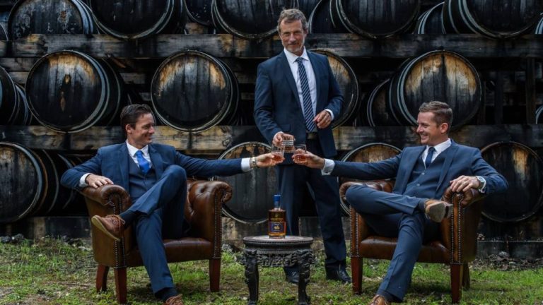 a group of people sitting and standing in front of a barrel